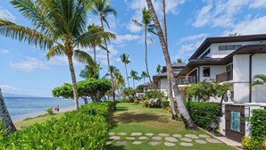 A resort with a well-maintained lawn, palm trees, and a view of the ocean. - Puunoa  - CoralTree Residence Collection (Lahaina)