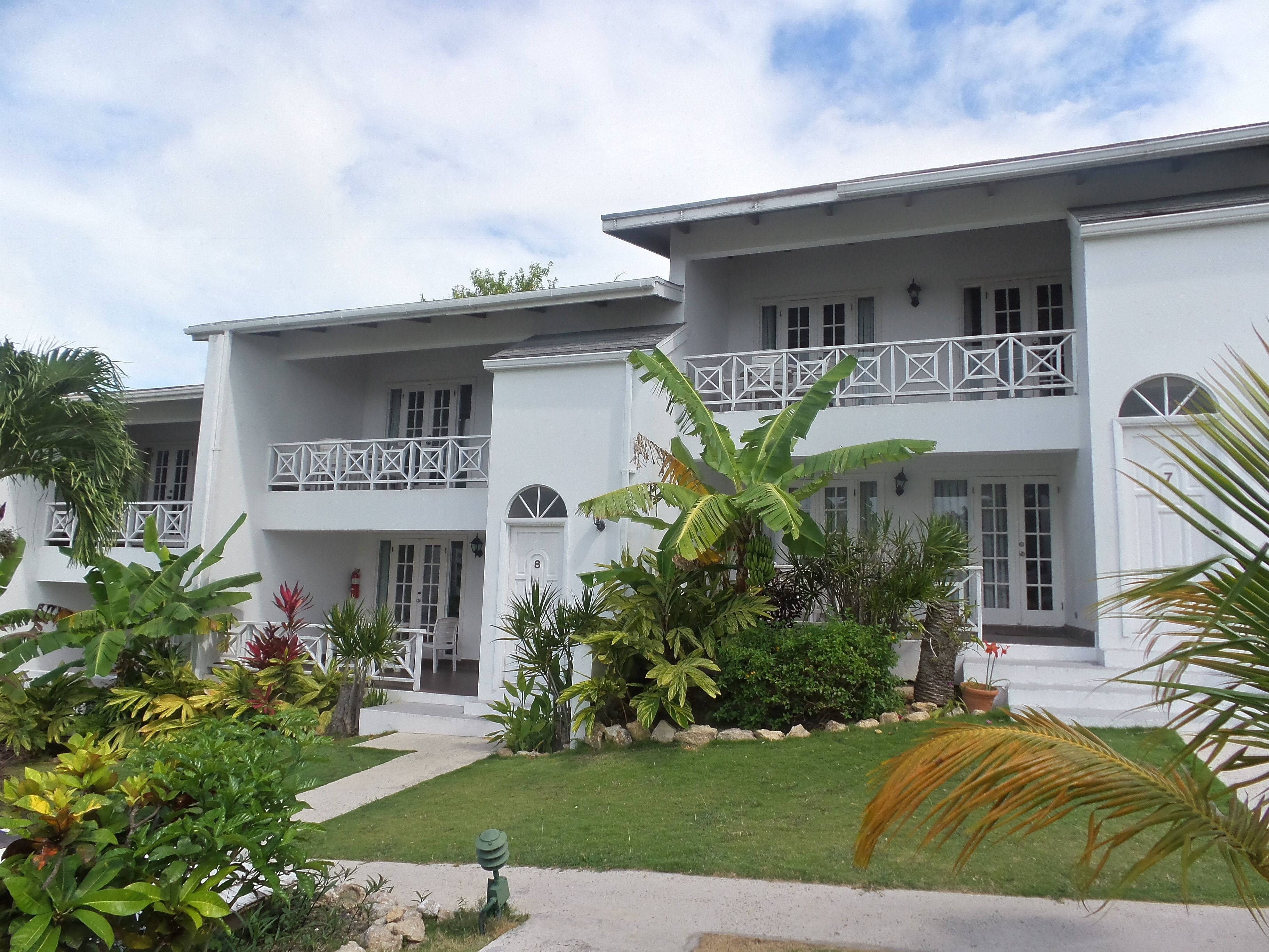 A two-story building with a white exterior, a balcony with white railings, and a number '8' on the door.