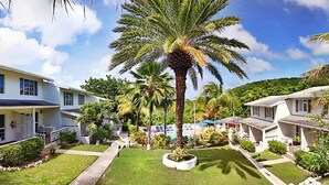 A residential area with two houses, a well-maintained lawn, and palm trees. - Dickenson Bay Cottages (St. John's)
