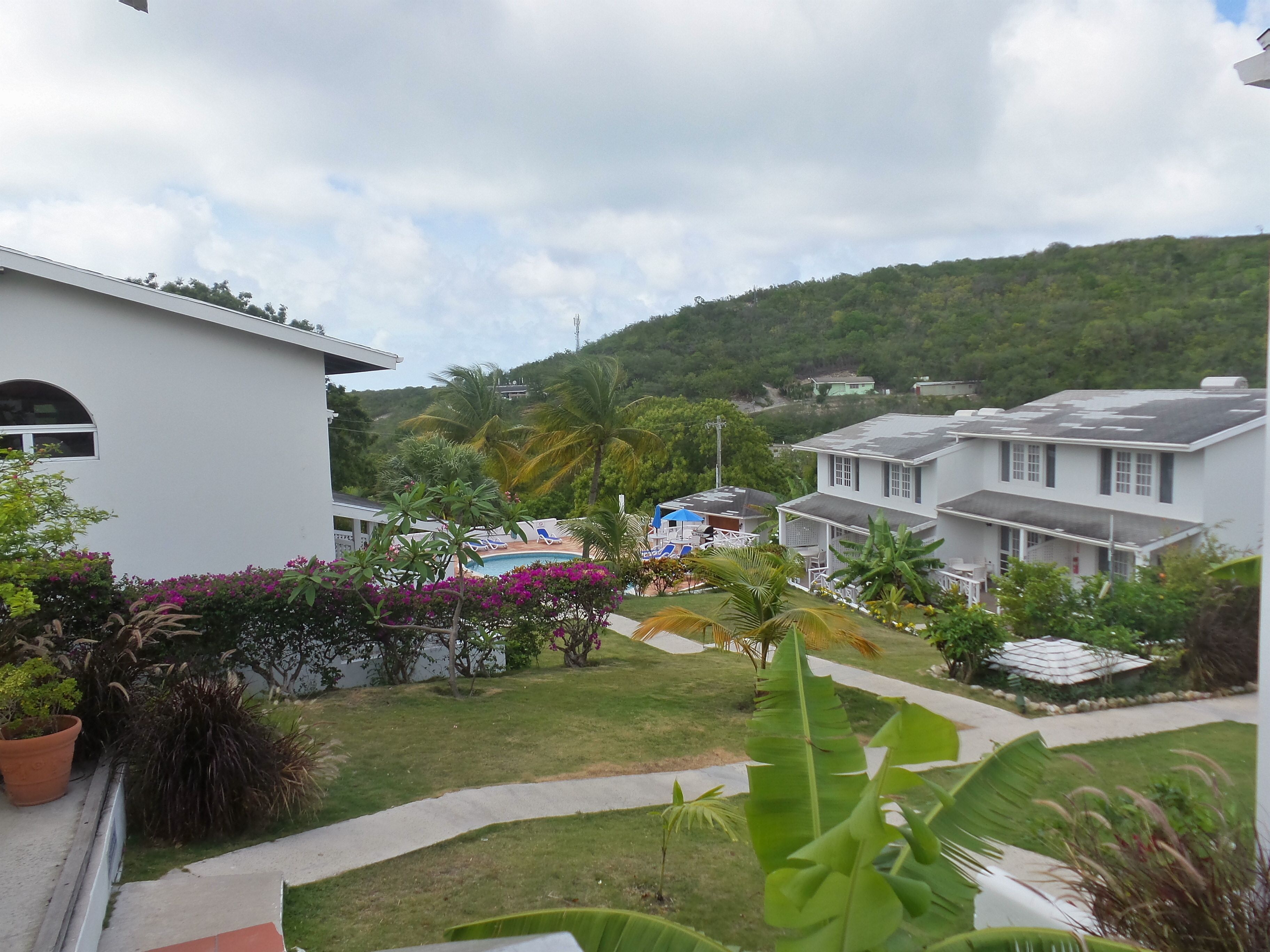 Um bairro residencial com casas brancas, piscina e vegetação exuberante.