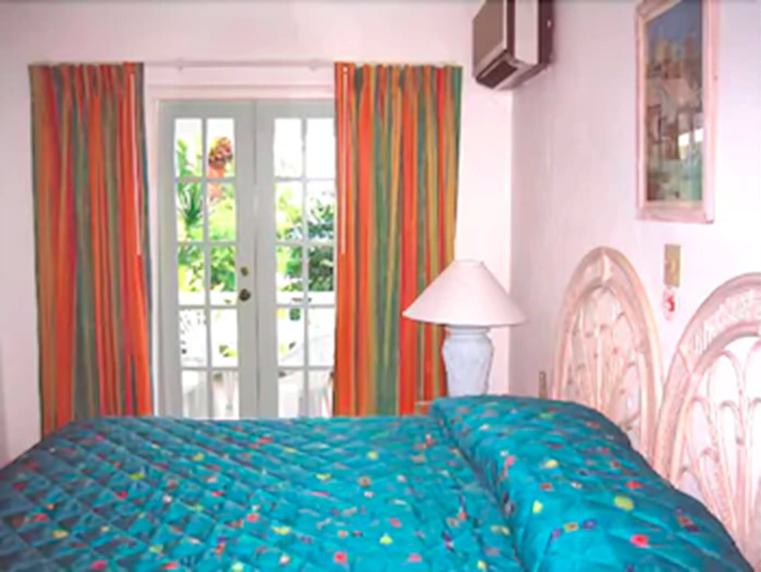 A bedroom with a bed, curtains, a lamp, and a door.