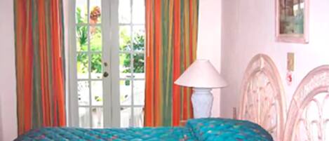 A bedroom with a bed, curtains, a lamp, and a door.