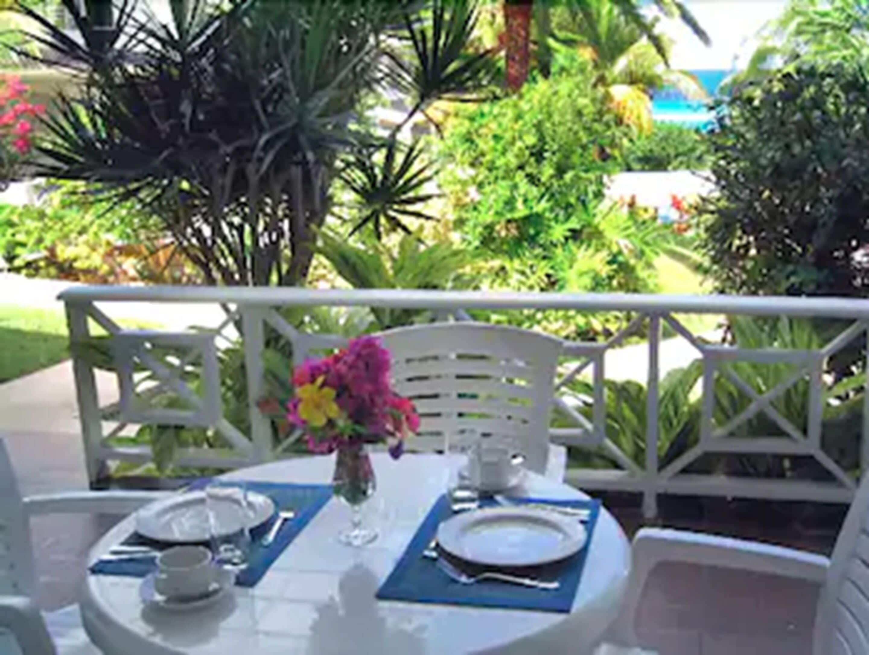 A round table with a white tablecloth, set with plates, cutlery, and a vase with flowers.