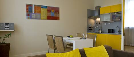 Un espacio habitable compacto con comedor, kitchenette y un sofá con cojines amarillos.