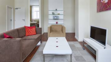 A modern living room with a sofa, a coffee table, a TV, and a bookshelf.