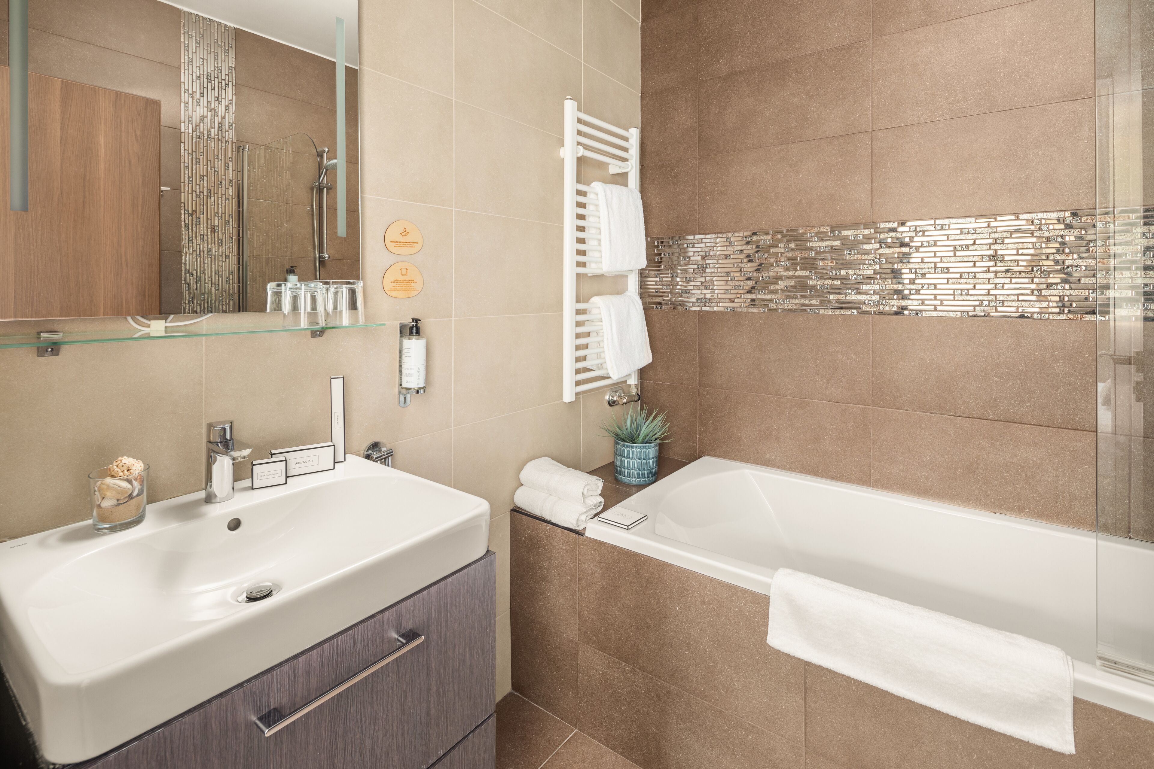 Une salle de bain moderne dotée d’un grand lavabo, d’une baignoire et d’une cabine de douche en verre.