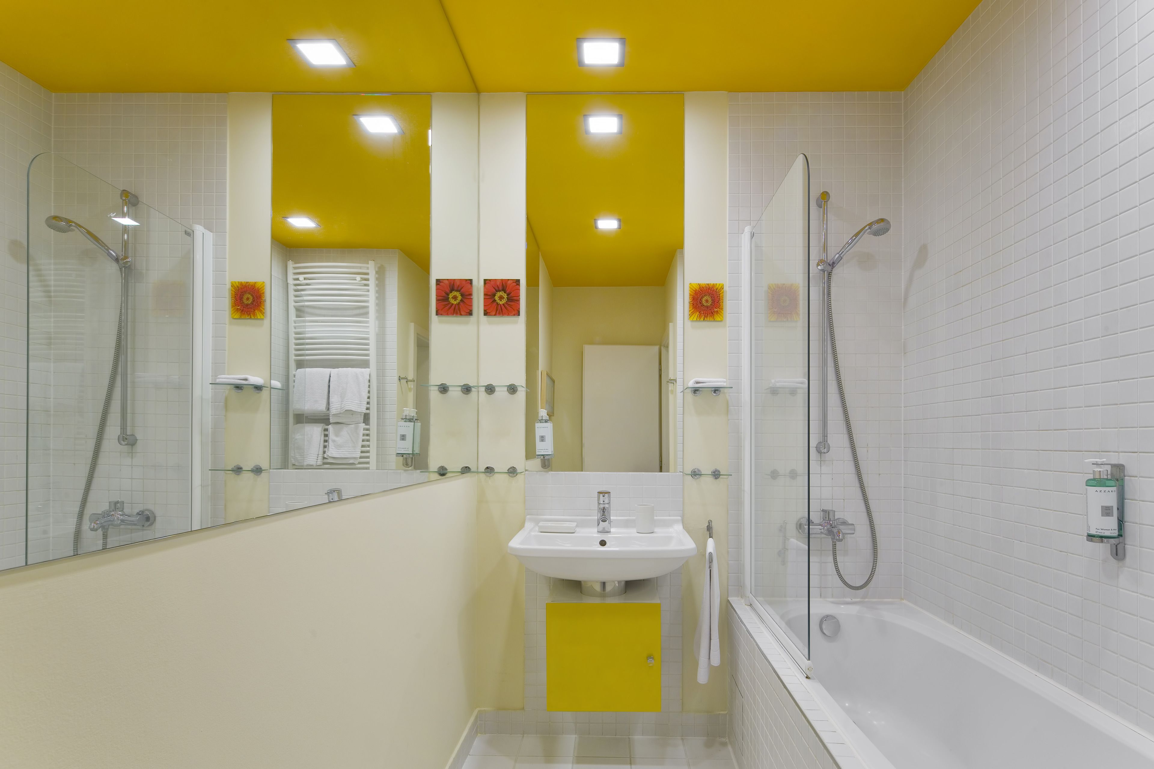 Une salle de bain avec un plafond jaune, des murs blancs, un lavabo, une baignoire et une douche.