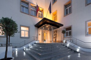 Ein Gebäude mit Glastür, Stufen, die hinaufführen, und Flaggen auf dem Dach.