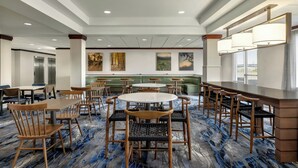 A hotel lobby with round tables, bar seating, and a green sofa area. - Fairfield Inn & Suites by Marriott Springdale (Springdale)