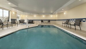An indoor swimming pool with a tiled border, surrounded by lounge chairs and a wooden deck. - Fairfield Inn & Suites by Marriott Springdale (Springdale)