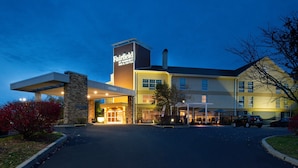 Un hotel Fairfield Inn & Suites con fachada de piedra, un acceso cubierto y un estacionamiento.