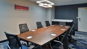A conference room with a long table, six chairs, a whiteboard, and a door.