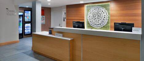 Un comptoir d’accueil avec une plaque nominative, un élément décoratif mural et un ordinateur Lenovo.