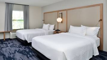 Une chambre d’hôtel avec deux lits, une grande fenêtre avec des rideaux, une lampe fixée au mur et un radiateur.