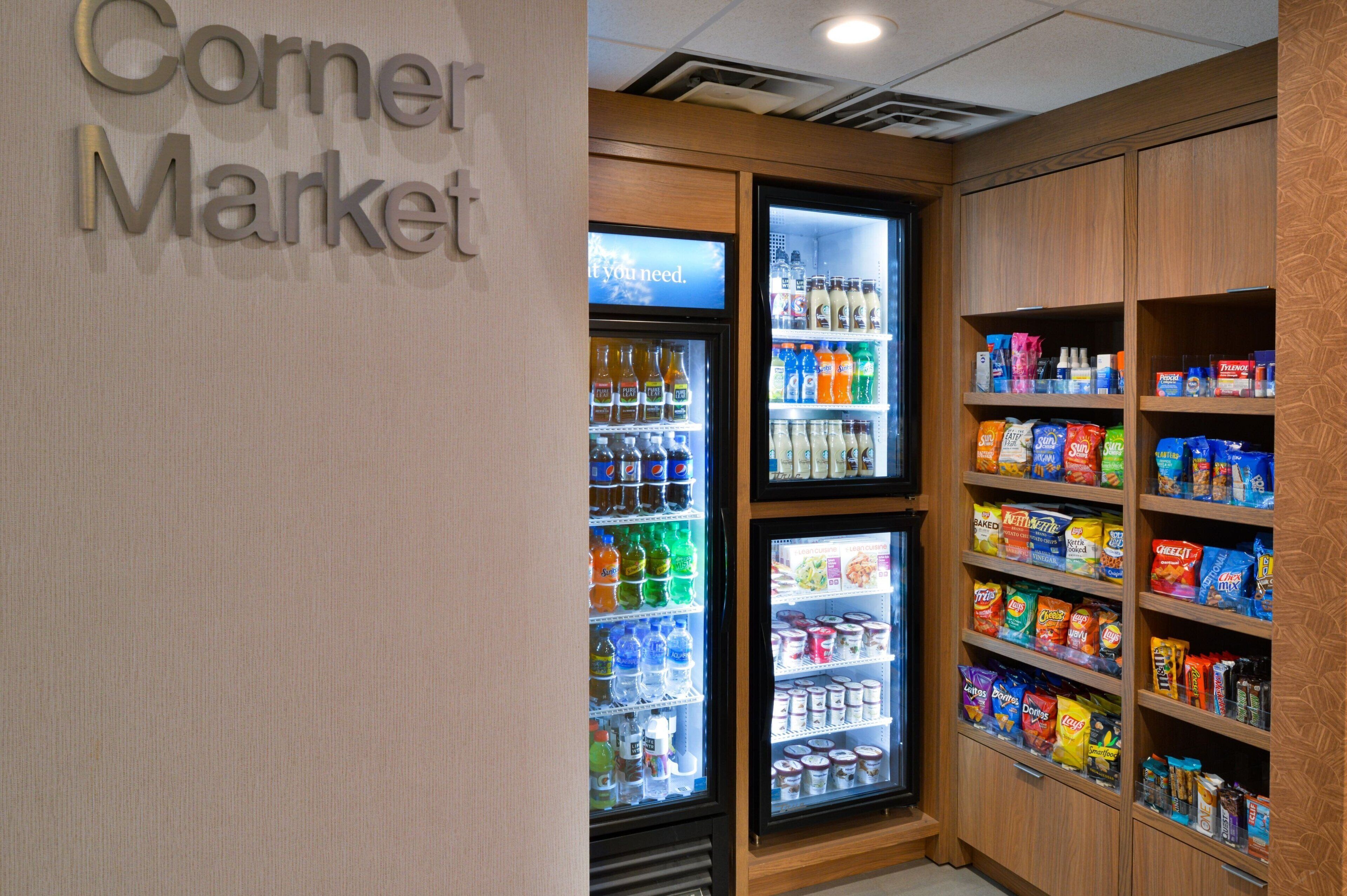 Une petite épicerie de quartier avec des distributeurs de boissons réfrigérés et des étagères remplies de collations et de boissons.