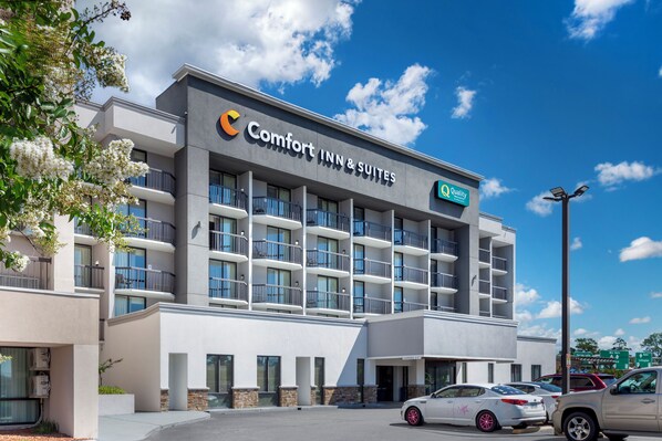 A Comfort Inn & Suites building with multiple balconies, a parking lot, and a clear blue sky.