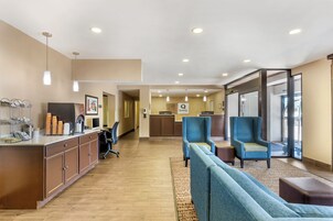A hotel lobby with a reception desk, seating area, and a view of the reception.
