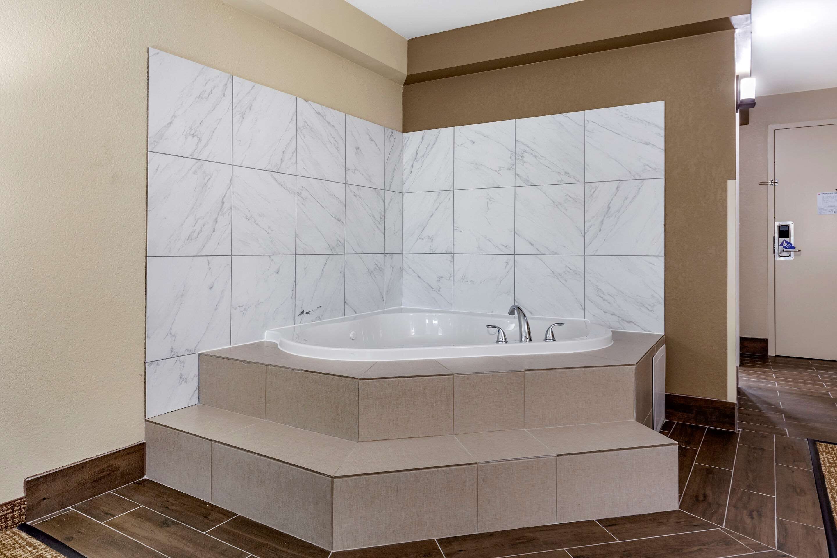 A modern bathroom with a freestanding bathtub, marble tiles, and a wooden floor.