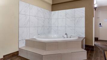A modern bathroom with a freestanding bathtub, marble tiles, and a wooden floor.