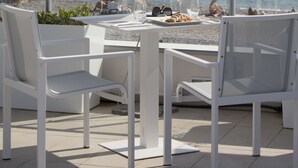 A terrace with a table, chairs, and a white umbrella overlooking the sea. - Mercure Villeneuve Loubet Plage (Villeneuve-Loubet)