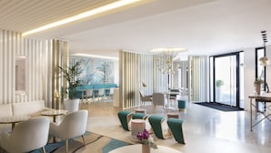 A modern hotel lobby with seating areas, a reception desk, and a large window providing natural light. - Mercure Villeneuve Loubet Plage (Villeneuve-Loubet)