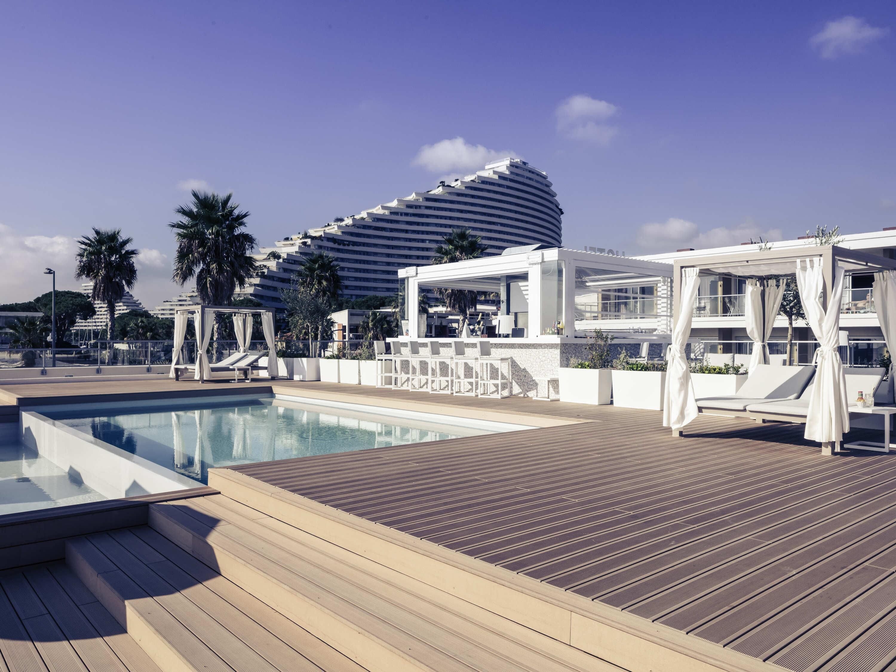 Un área de piscina con una piscina moderna, sillas de descanso y un edificio de diseño curvo singular.