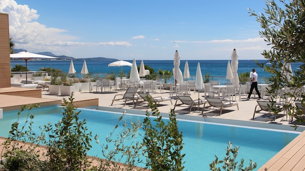 A poolside area with lounge chairs and umbrellas, overlooking a body of water. - Mercure Villeneuve Loubet Plage (Villeneuve-Loubet)