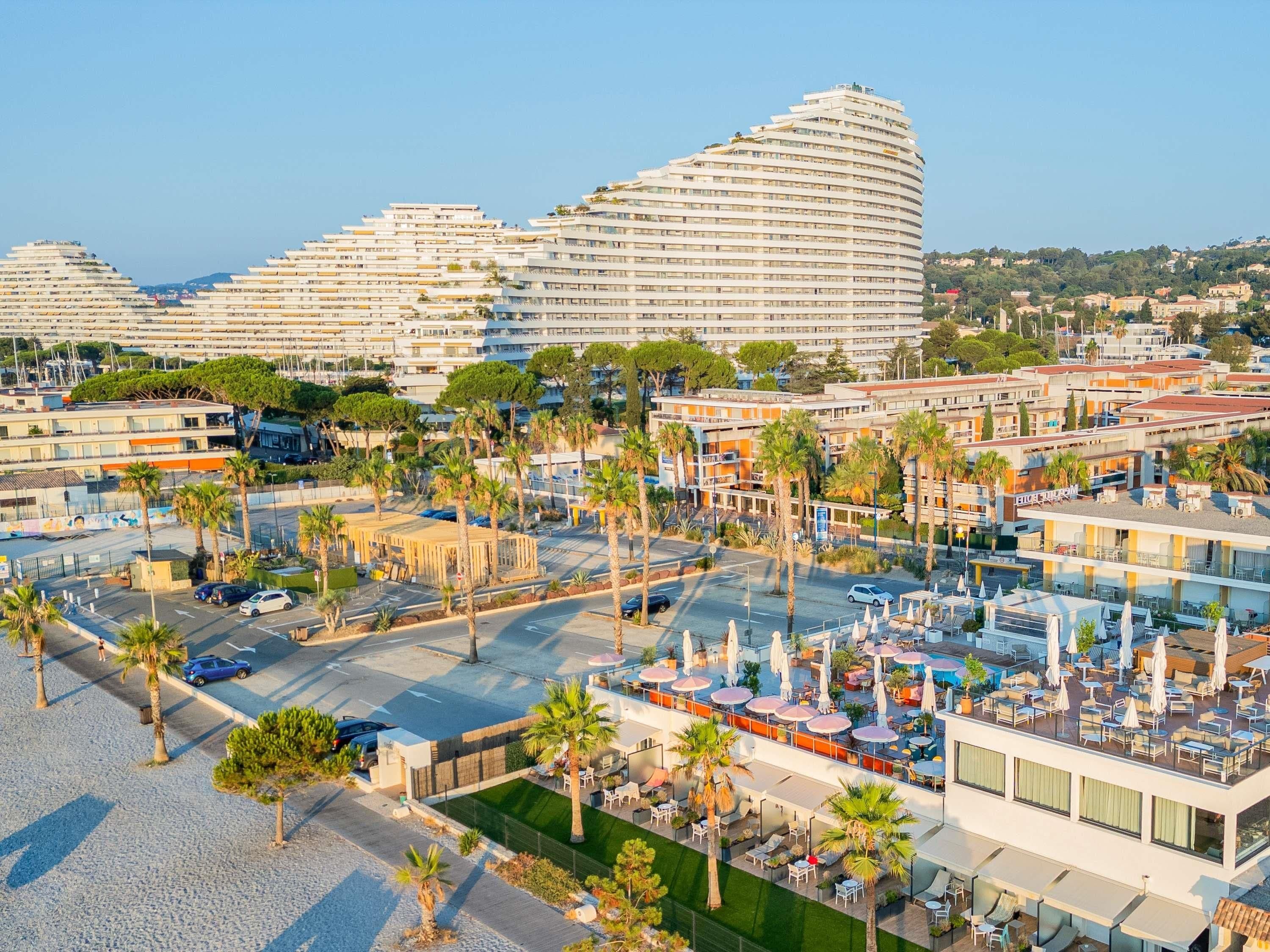 A hotel with multiple floors, outdoor seating areas, and a parking lot.