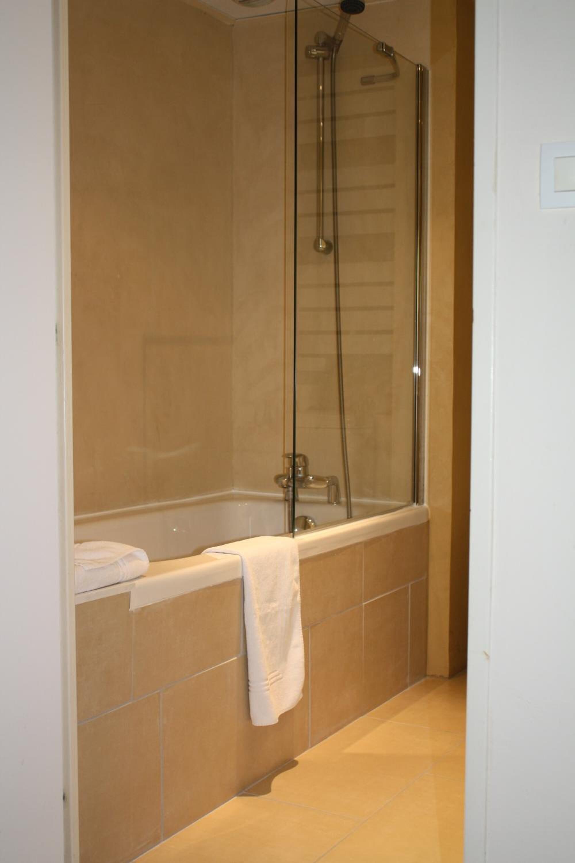 A bathroom with a glass-enclosed shower, a bathtub, and a towel hanging on the wall.