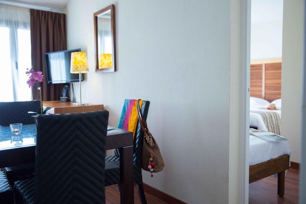 A hotel room with a bed, a desk with a chair, a television, and a lamp.