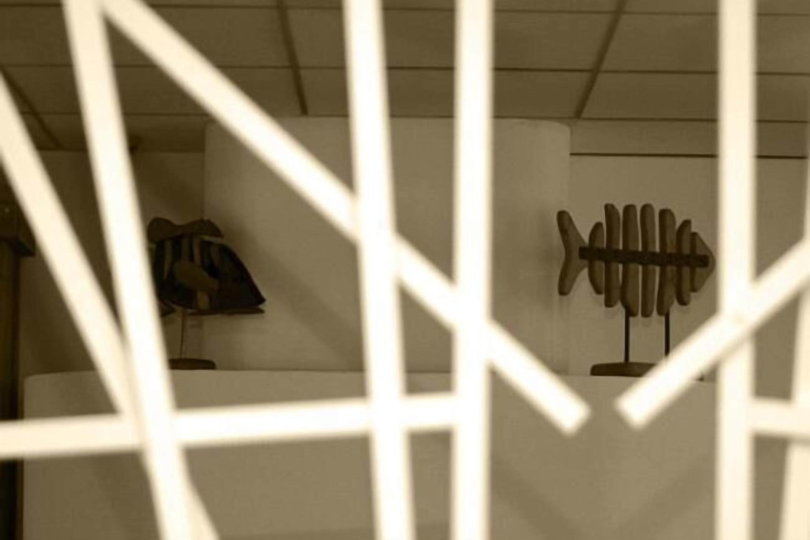 Une pièce dotée d’une fenêtre au motif géométrique, d’un porte-manteau et d’un luminaire fixé au mur.