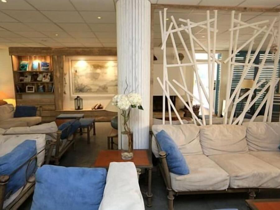 Una sala de estar acogedora con un sofá, sillones, una mesa de centro y una estructura decorativa blanca.
