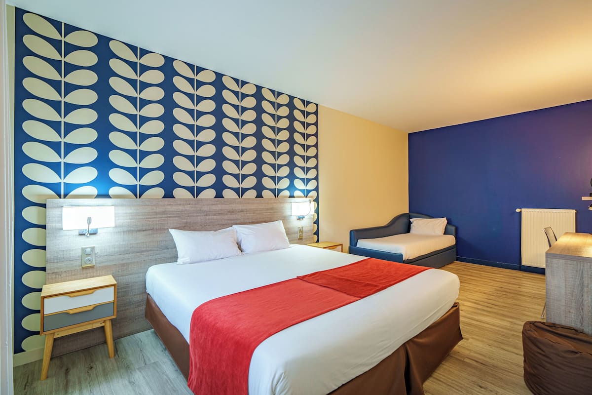 Une chambre d’hôtel avec un grand lit, une table de chevet, une chaise et un bureau.