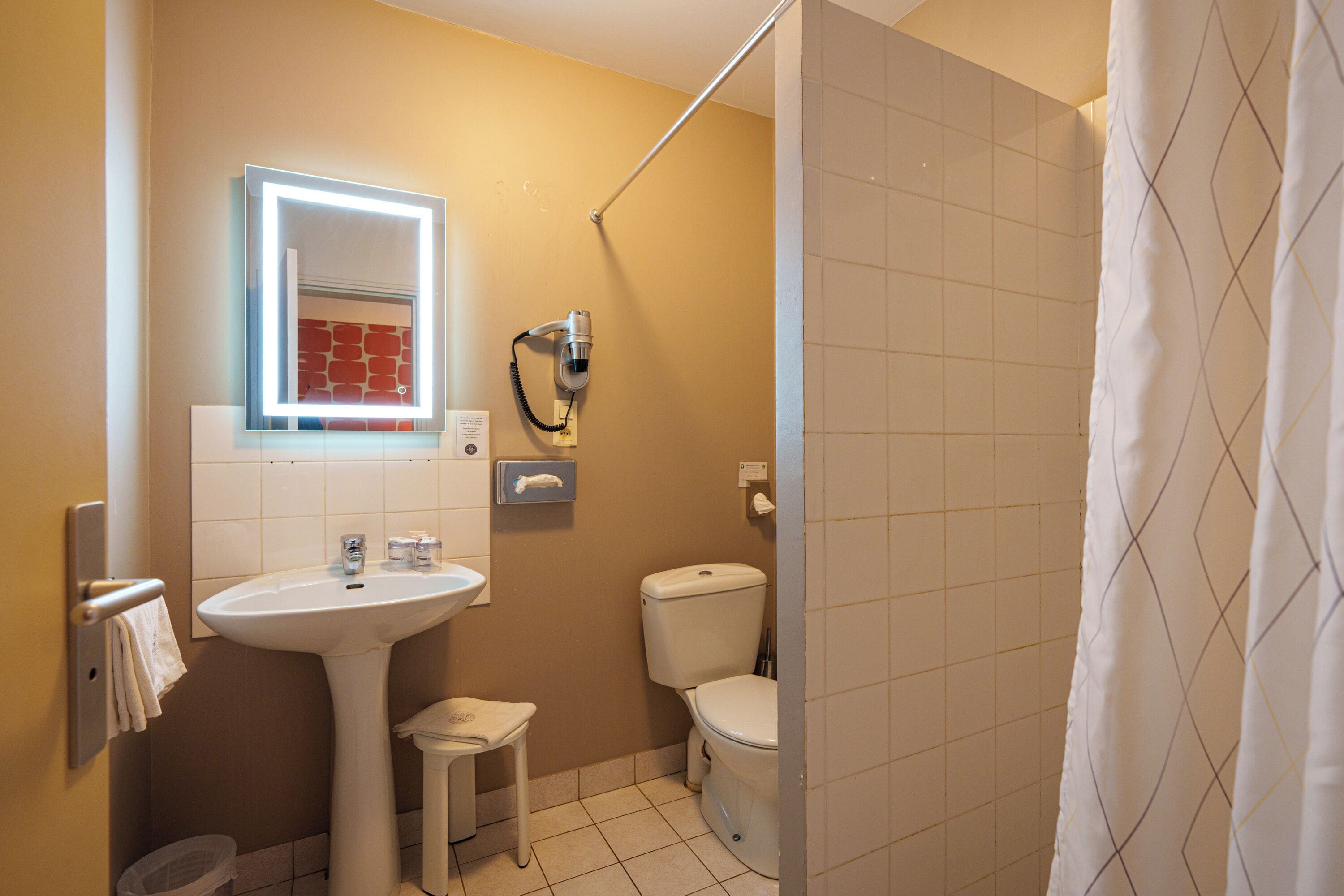 Un baño con lavamanos, espejo, inodoro y cortina de ducha.