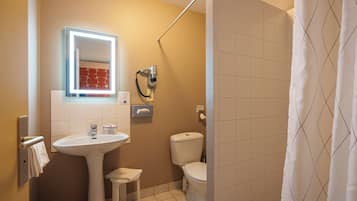 Un baño con lavamanos, espejo, inodoro y cortina de ducha.