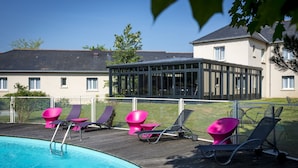 Une piscine avec des chaises longues et une véranda.