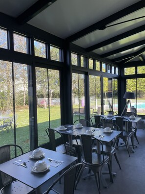 Ein Wintergarten mit Essplätze, großen Fenstern und Blick ins Freie.