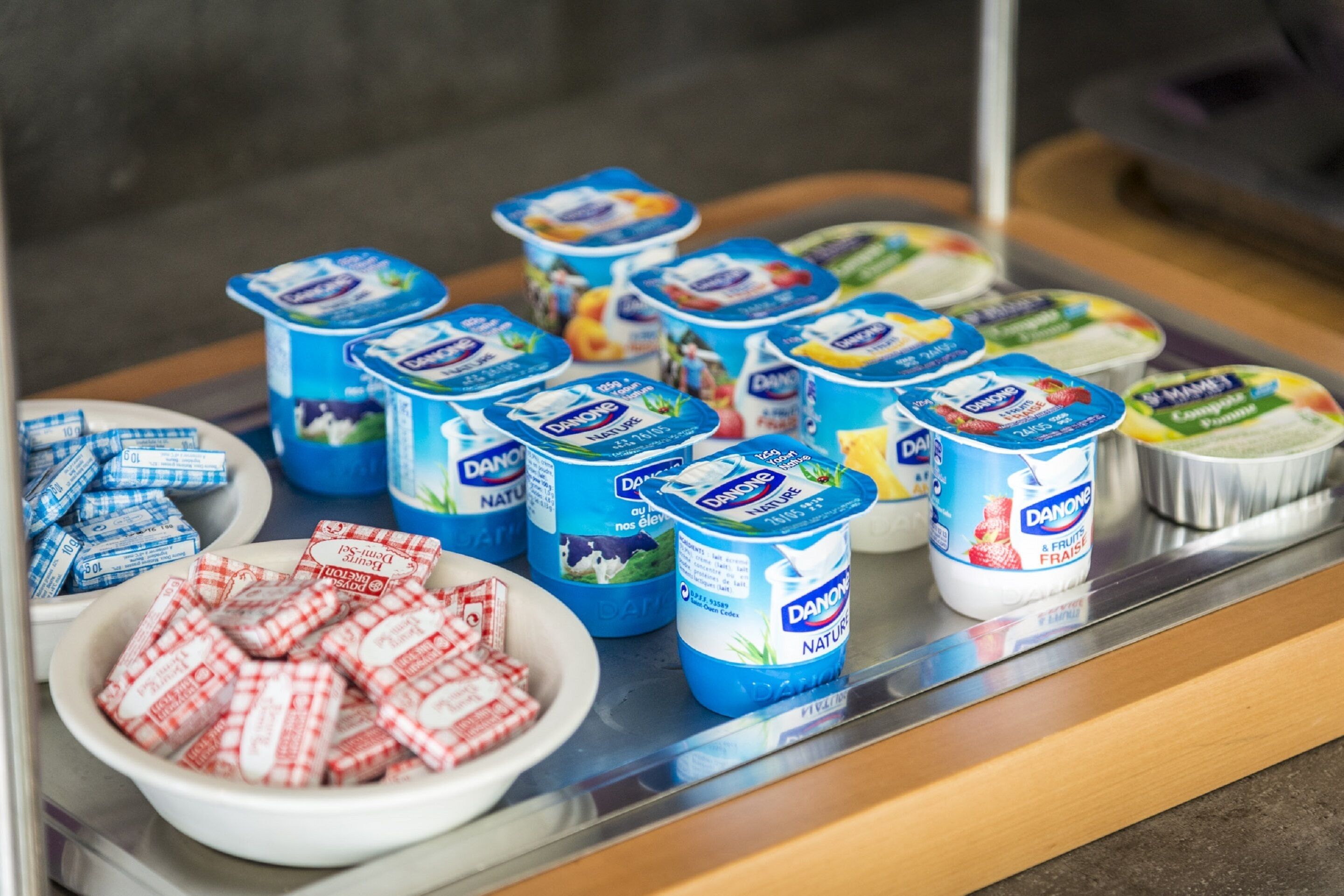 Una exhibición de recipientes y paquetes de yogur Danone sobre una encimera.