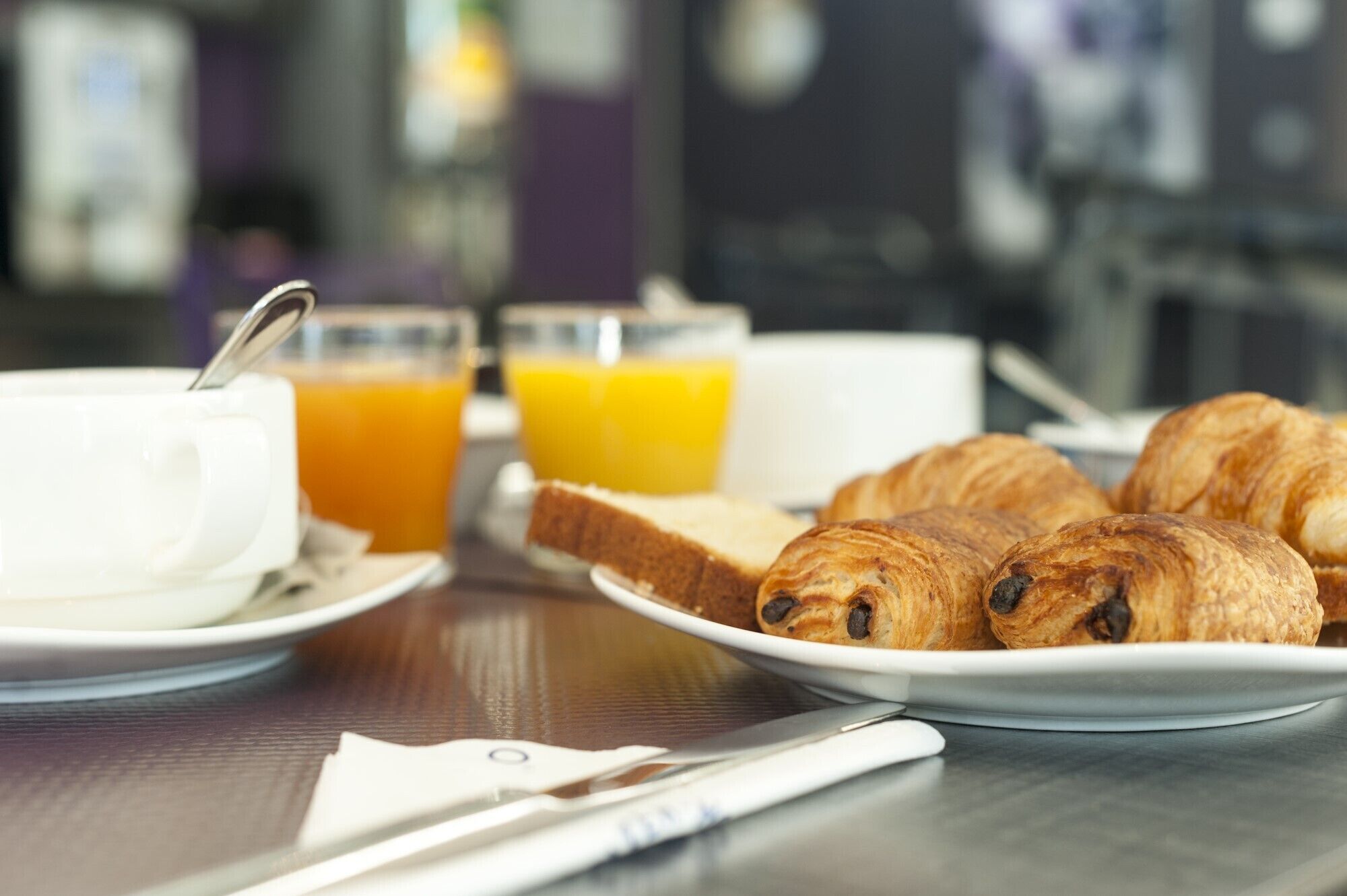 Una colazione con croissant, succo d'arancia e una tazza su un tavolo.
