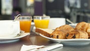 Una colazione con croissant, succo d'arancia e una tazza su un tavolo.