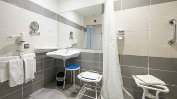 A bathroom with a sink, mirror, and a wheelchair-accessible bench.
