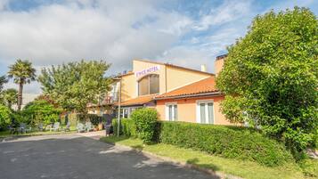 A hotel with a sign reading "O'Nice Hotel," a paved driveway, and a well-maintained lawn with chairs.