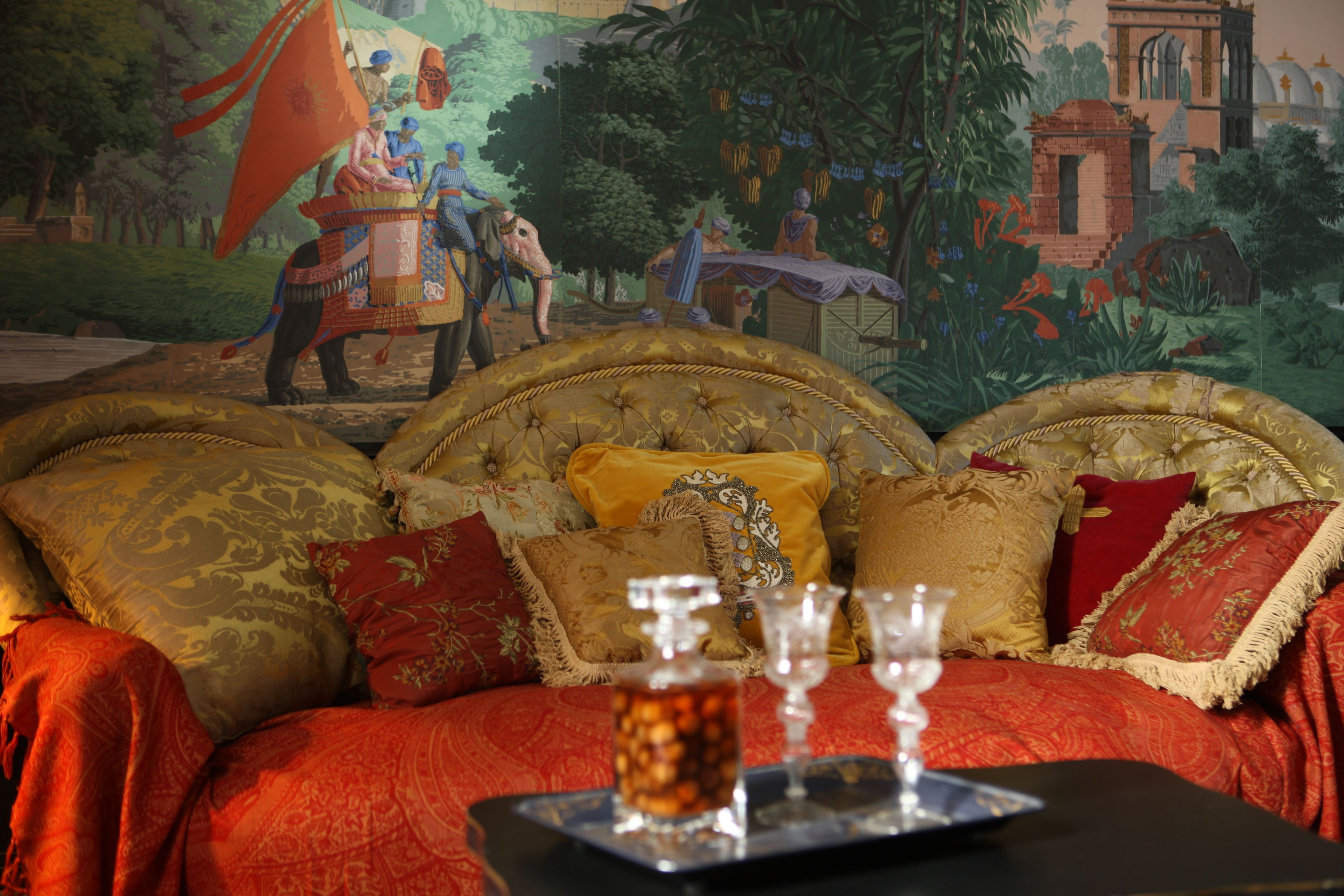 Una cama lujosa con almohadas decorativas y una bandeja con vasos y una botella.