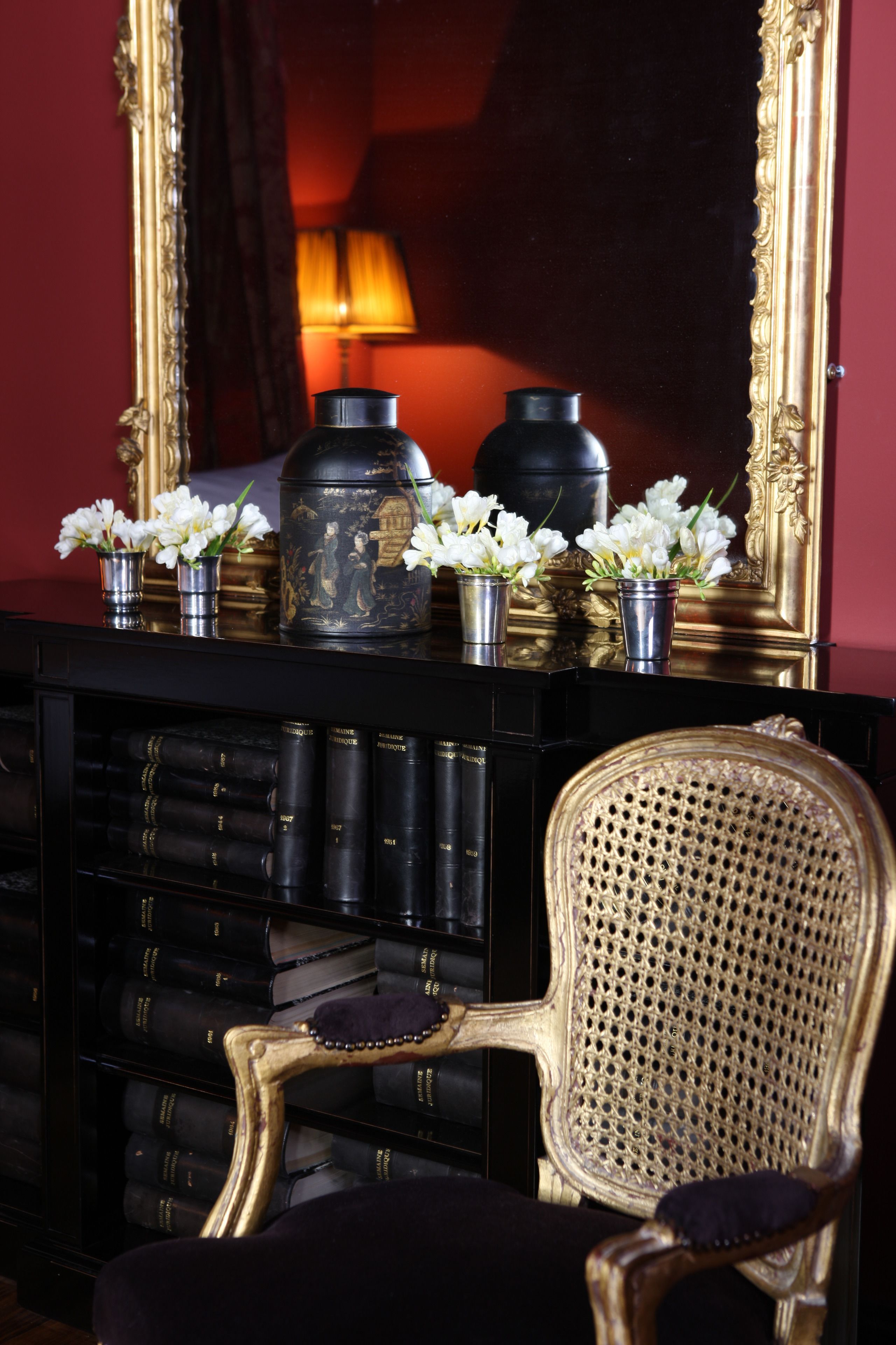 A room with a bookshelf, a chair, and a mirror.