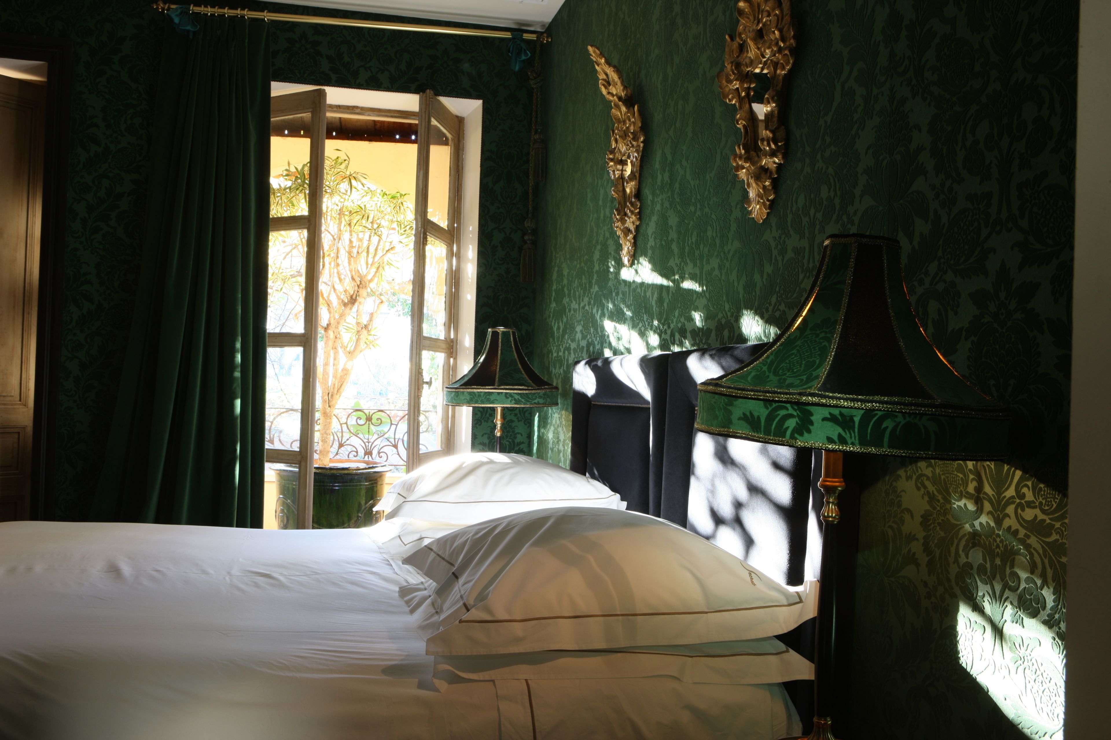 A room with a bed, a lamp, and a window with curtains.