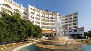 A hotel with a large fountain in front, surrounded by a pool and greenery. - Marhaba Royal Salem (Sousse)
