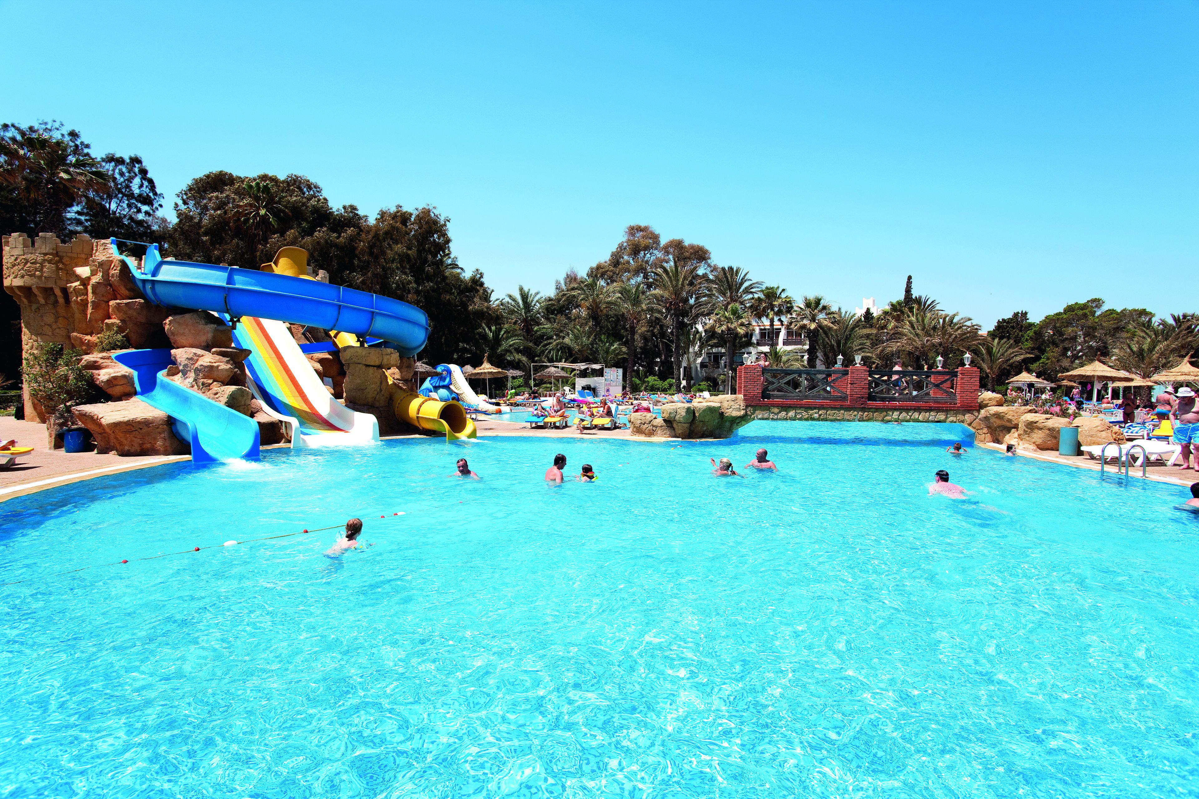 A swimming pool with a water slide and rock formations.