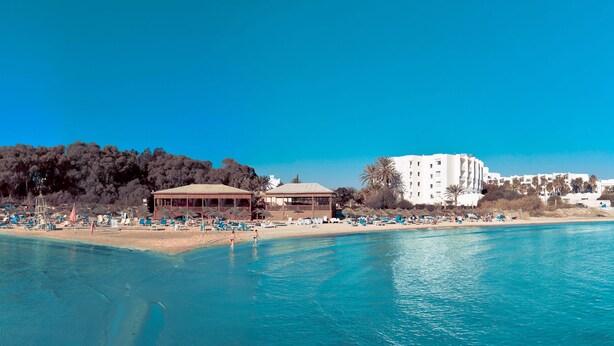 A coastal resort with beach umbrellas, a pool, and a building with multiple floors. - Marhaba Royal Salem (Sousse)