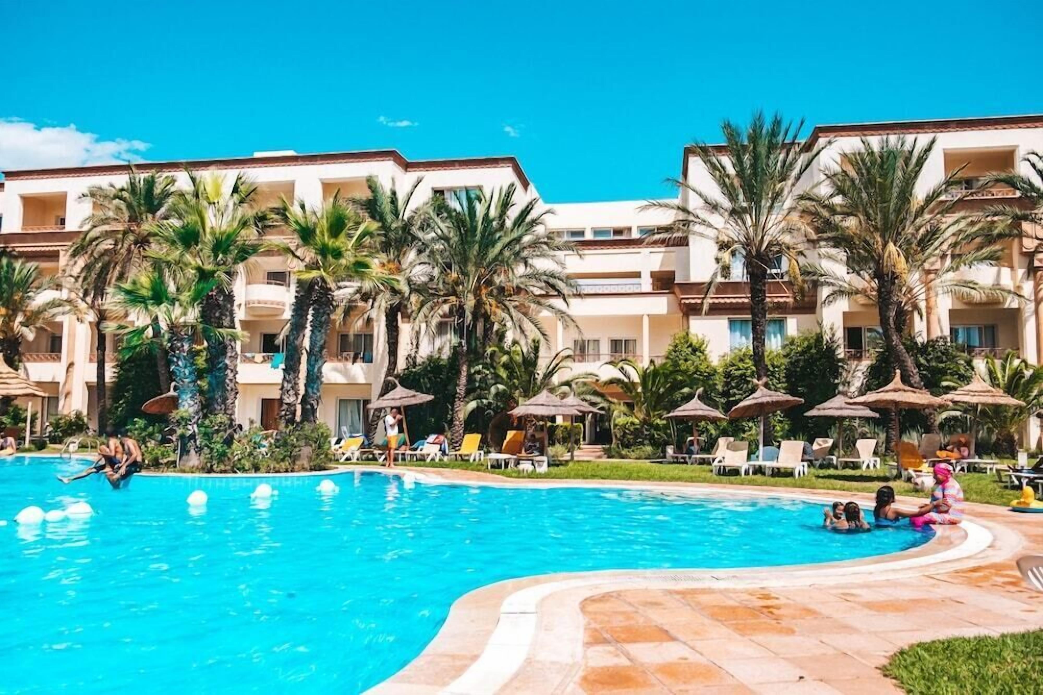 Una piscina cubierta, una piscina al aire libre, sombrillas, tumbonas