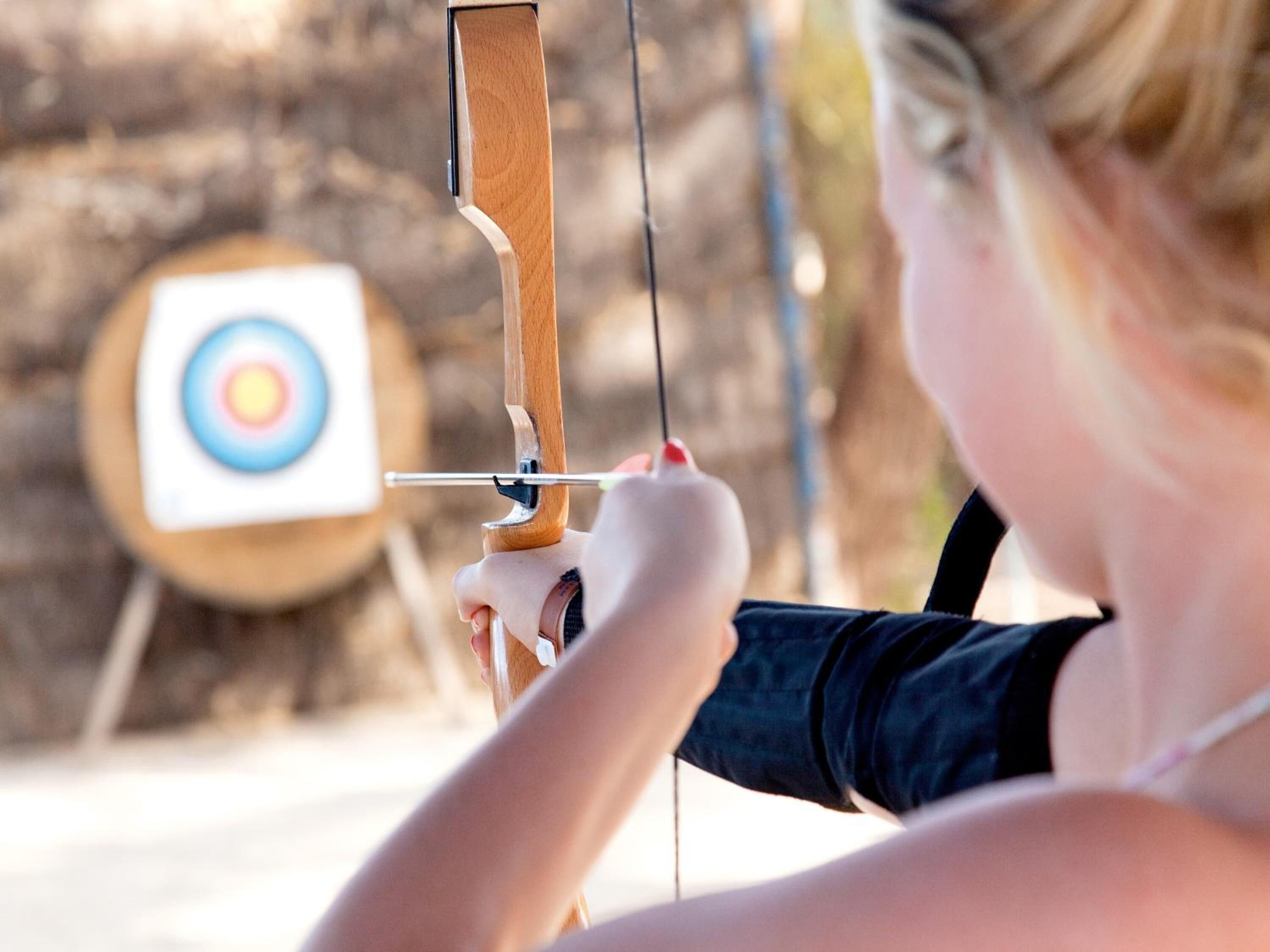 A person aiming a bow at a target.